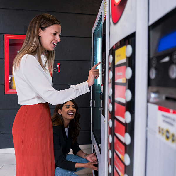Female Coworkers Looking At Vending Machine